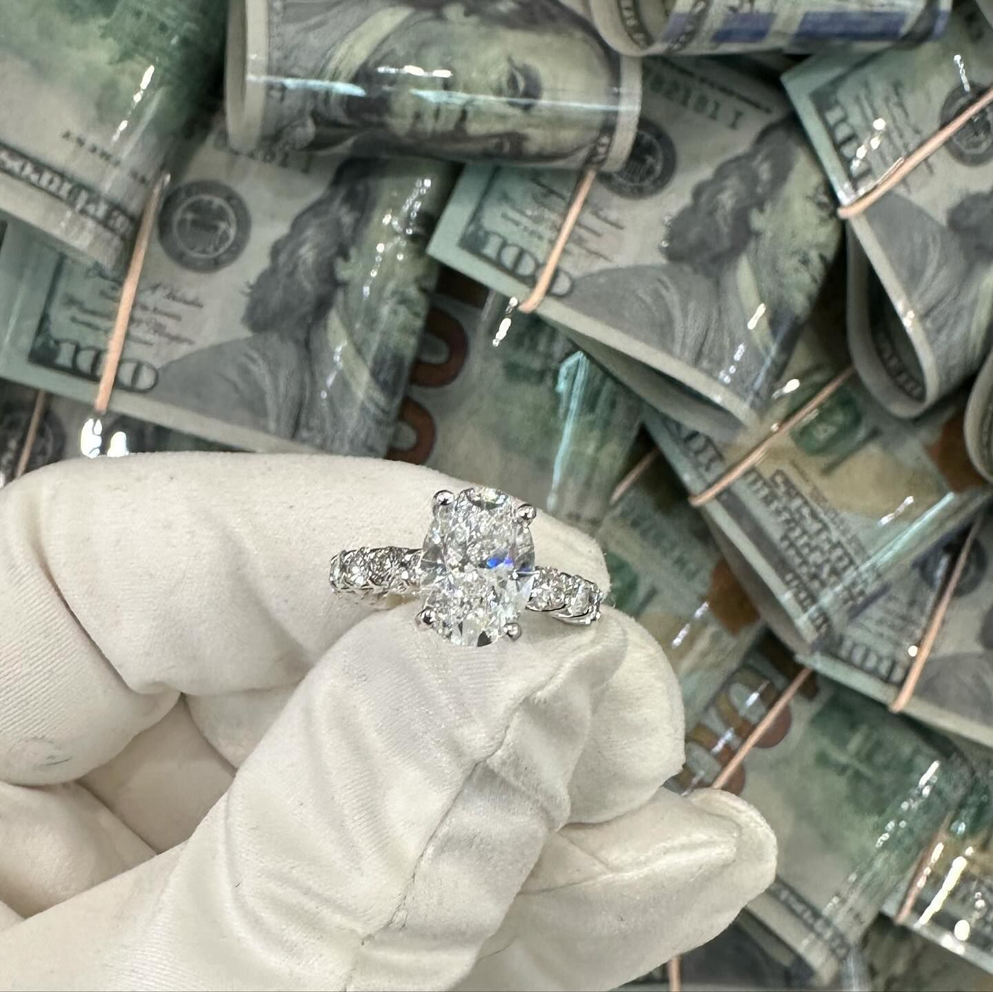 Gloved hand holding a silver diamond ring over stacks of bundled cash