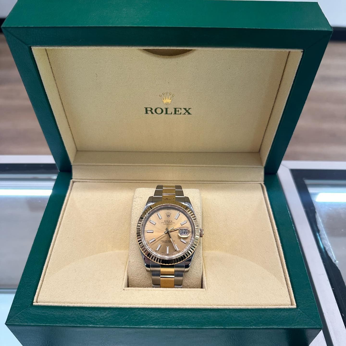 Rolex watch in green presentation box, gold-and-silver band and champagne dial.