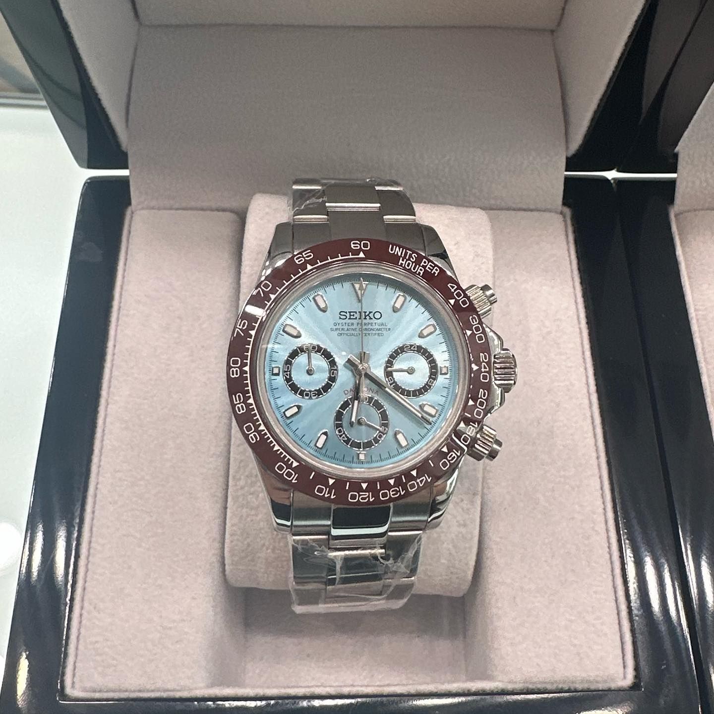 Silver chronograph watch with blue face in an open display box
