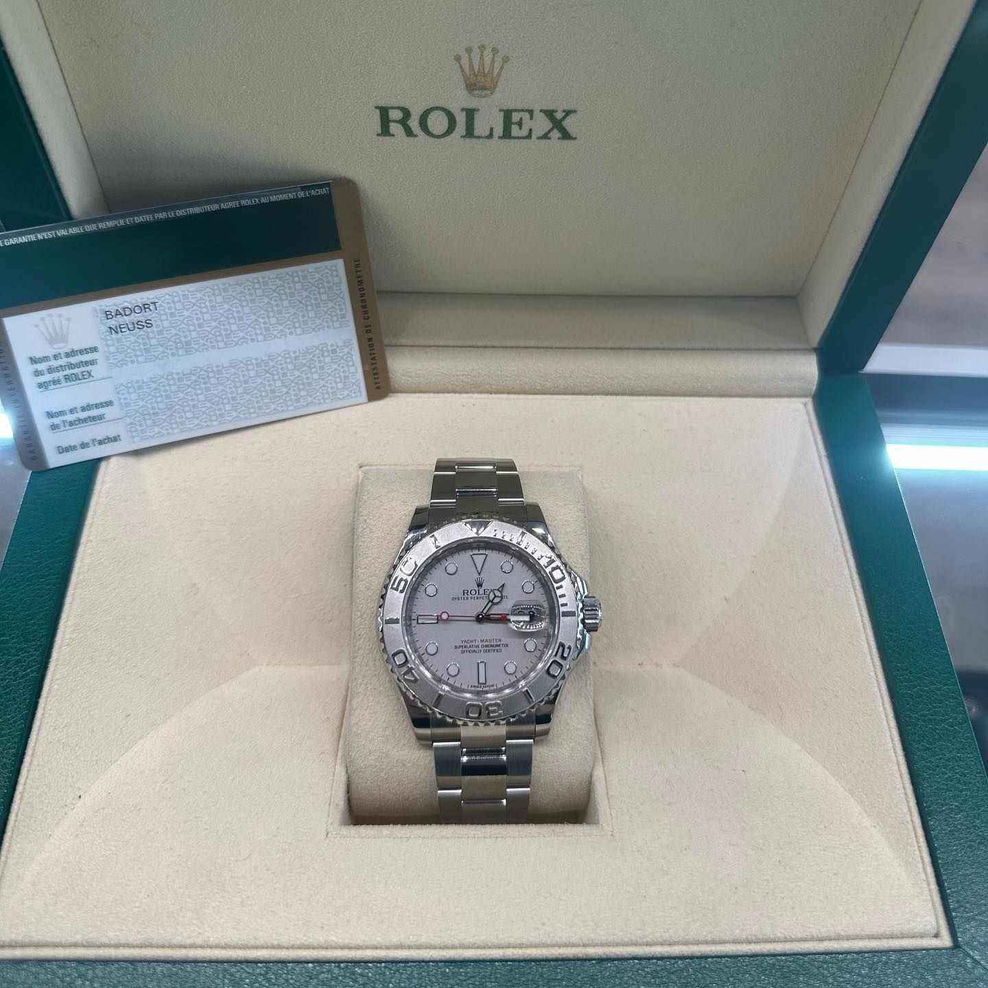 Rolex watch displayed in an open green presentation box with certificate card.