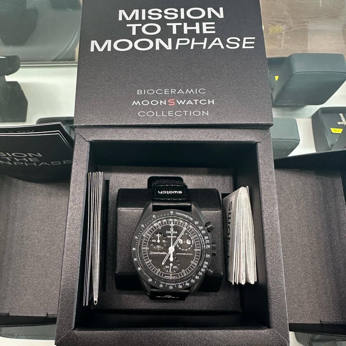 MoonSwatch Mission to the Moonphase watch in black box with gray straps and packaging text