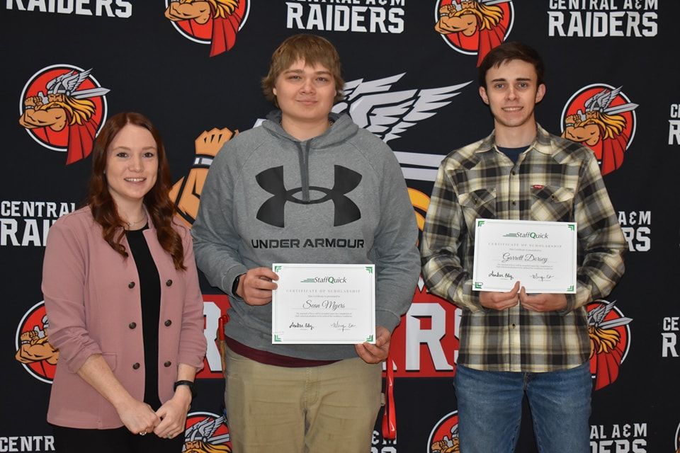 Three people stand in front of a backdrop with a school logo. A woman and two young men hold certificates.