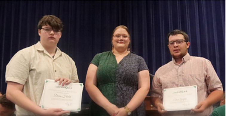 Three people hold certificates. A man, a woman, and another man stand in front of a blue curtain.