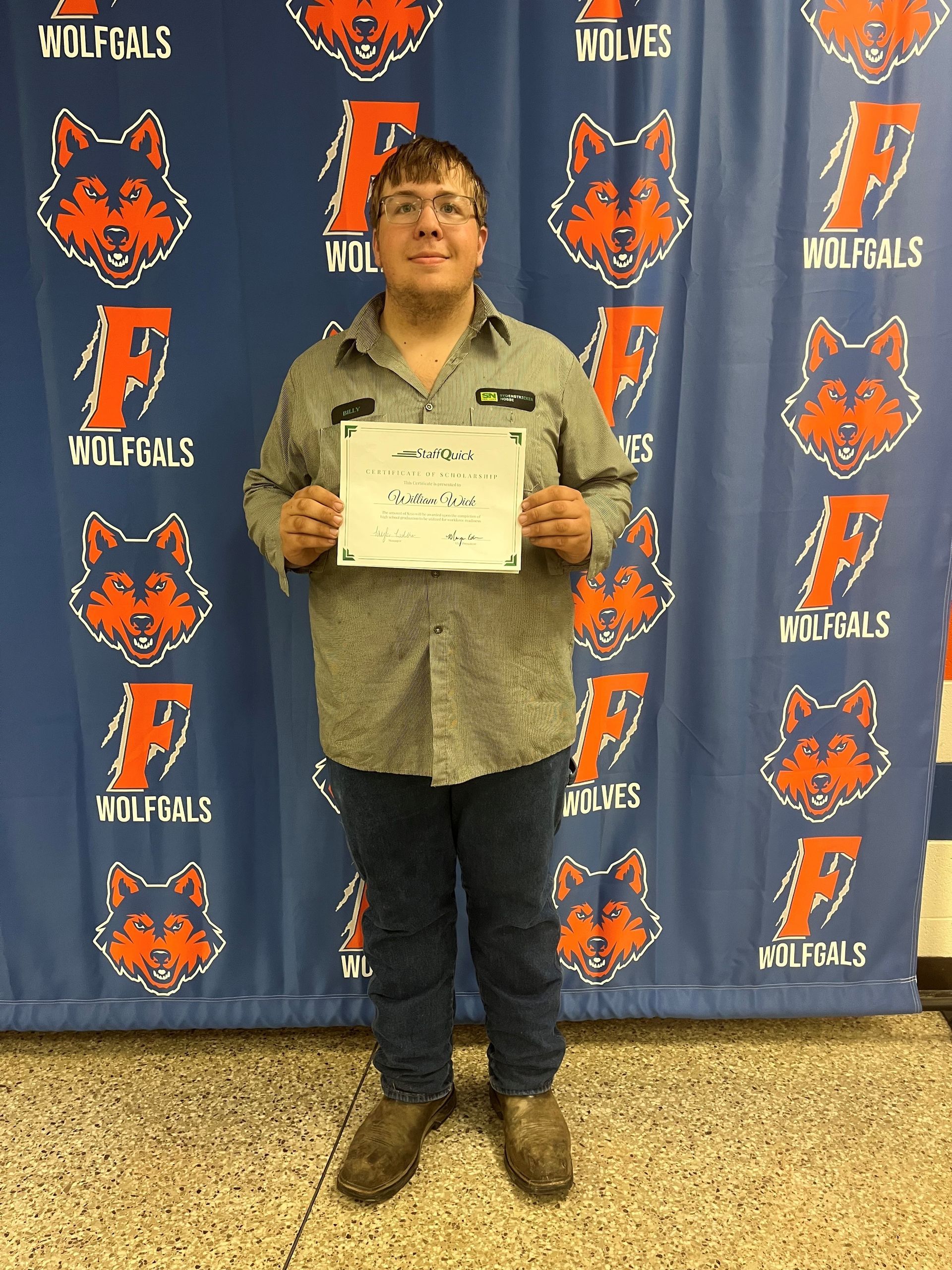 Person holding a paper in front of a Wolfpack backdrop.