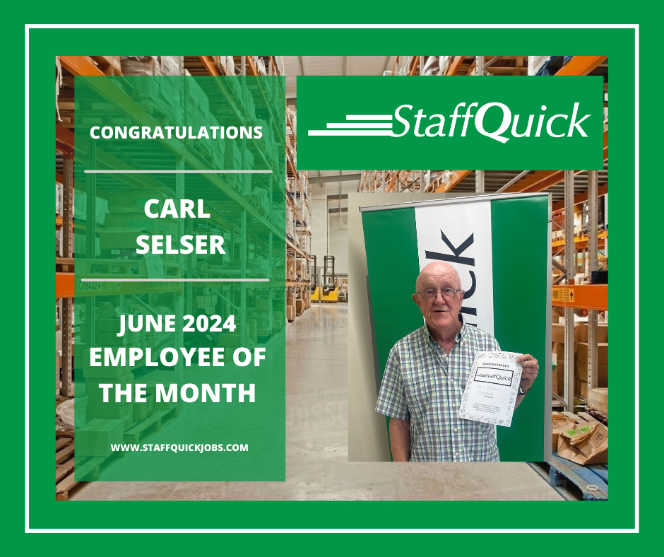 A man is holding a certificate in front of a warehouse.