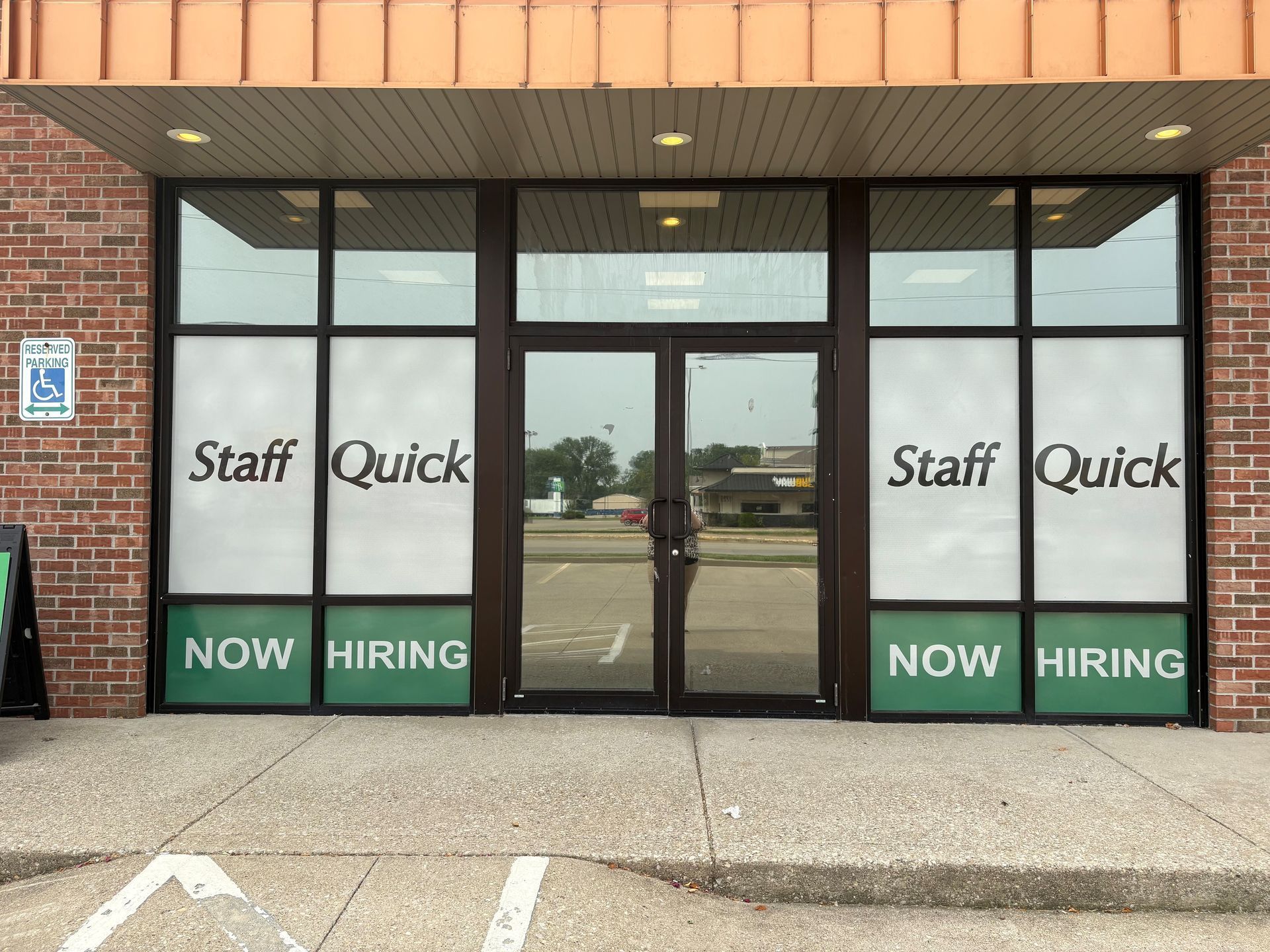 A store front with a sign that says staff quick now hiring