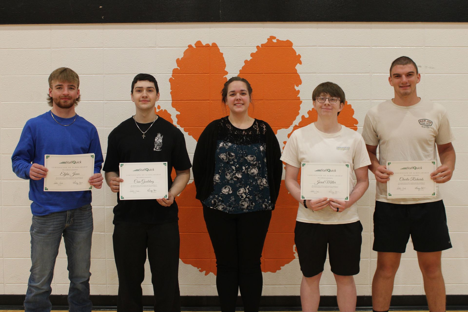 Five people holding certificates in front of an orange tiger paw logo.