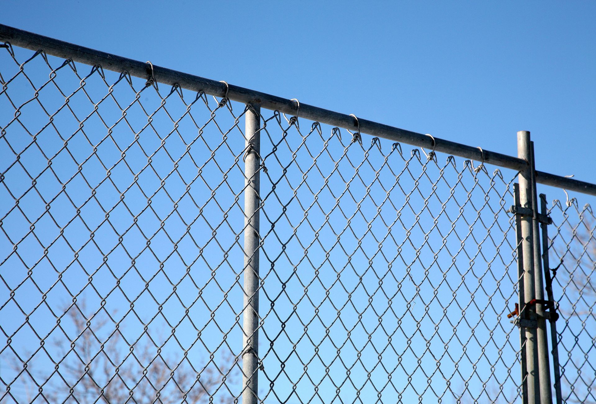 Chain-link fence against a clear, bright blue sky.