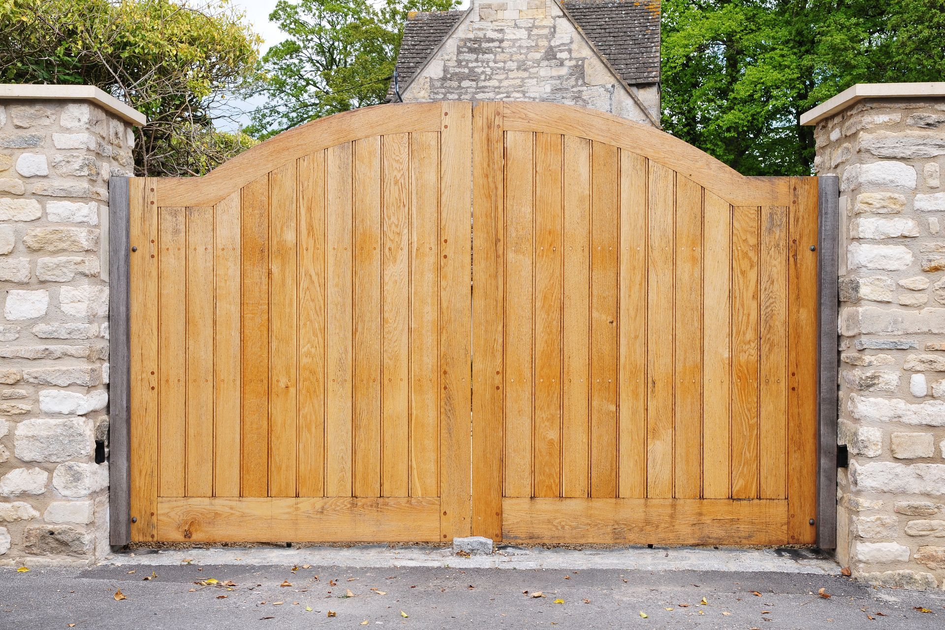 Wooden gate with vertical planks, between stone pillars.