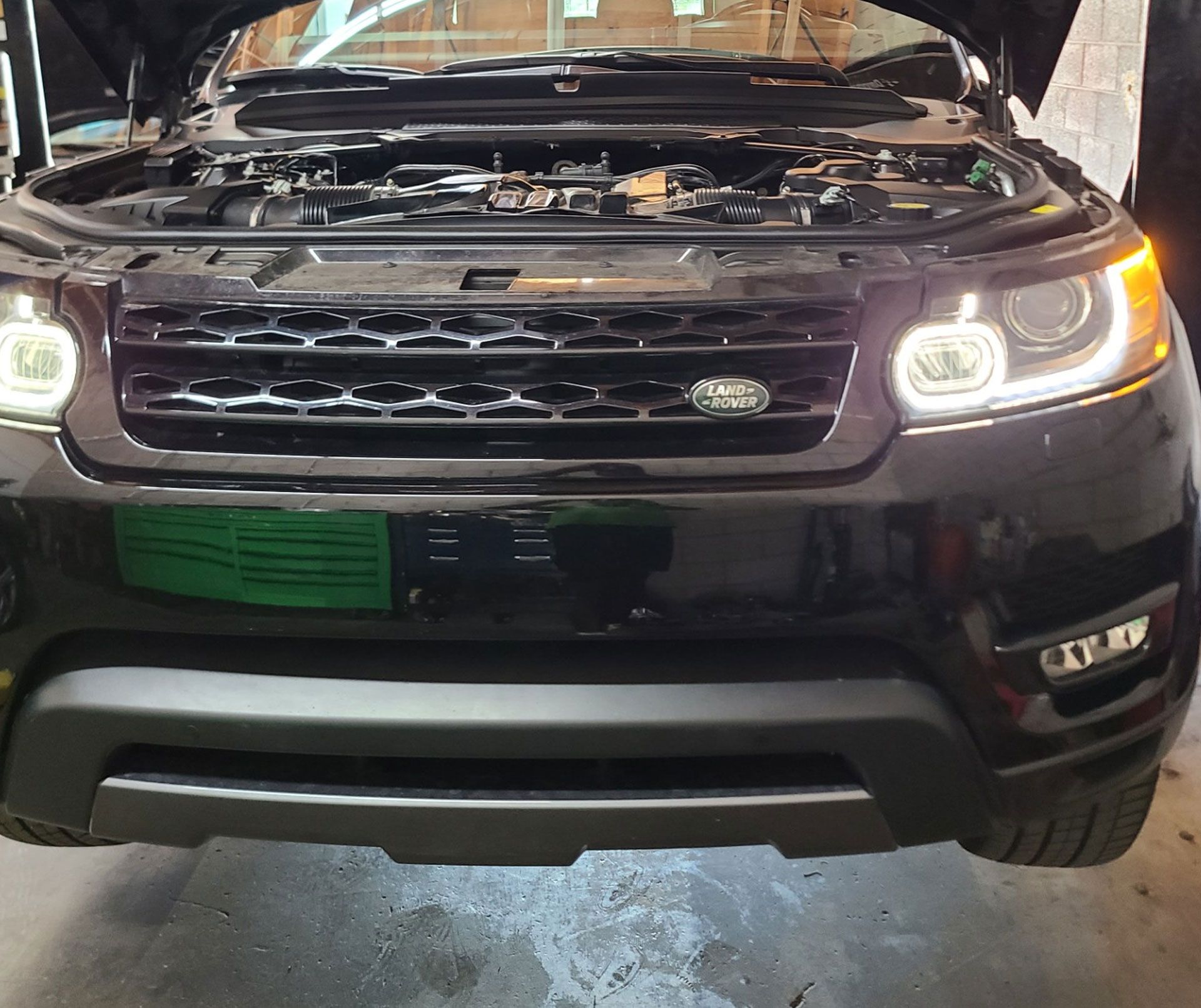 A black Range Rover with the hood up in a garage