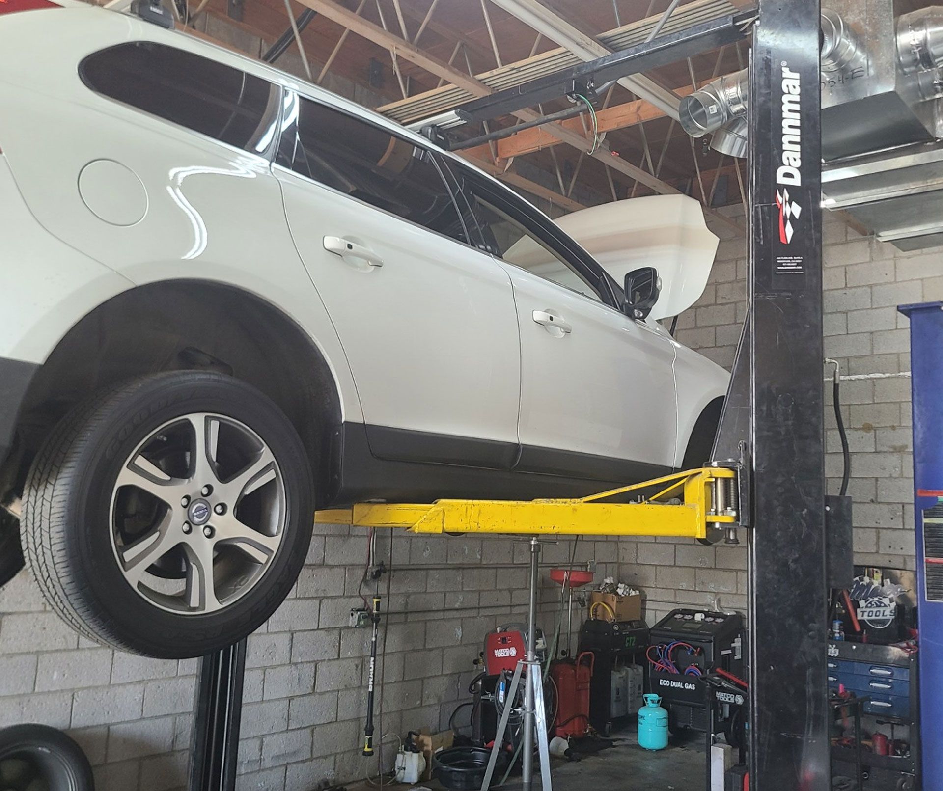 A white car is sitting on a lift in a garage.