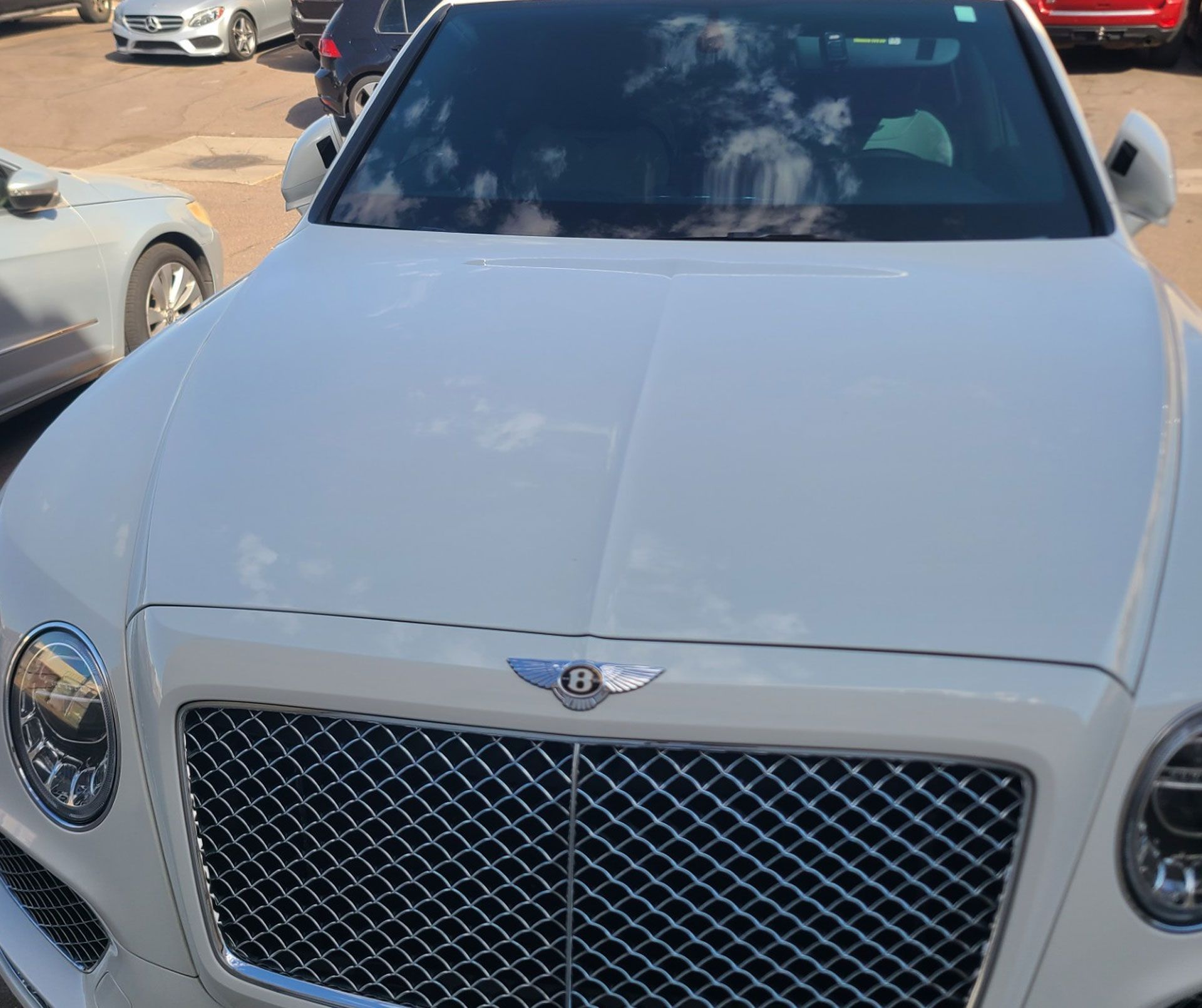 A white Bentley is parked in a parking lot.