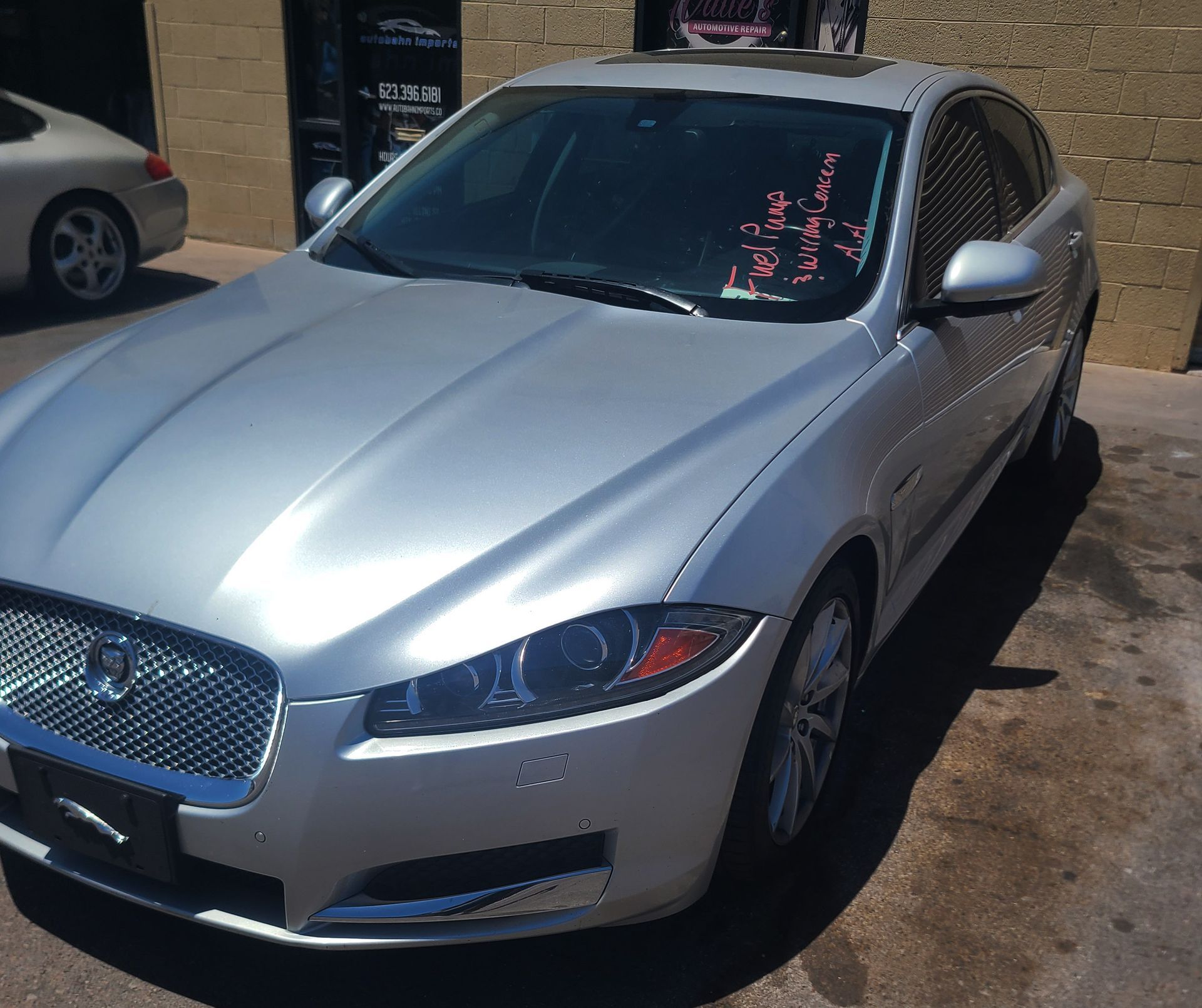 A silver jaguar is parked in front of a building