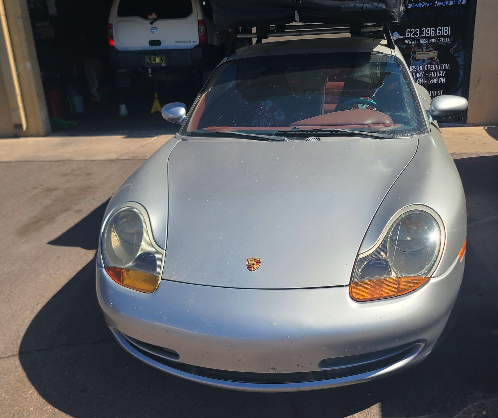 A silver Porsche is parked in front of a garage