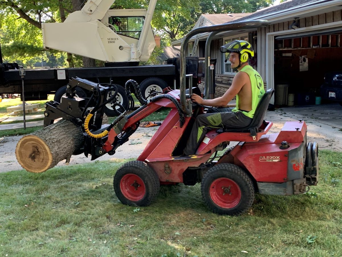 A man is riding a tractor with a crane attached to it.