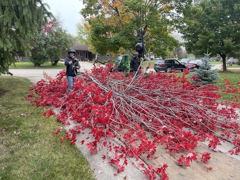 A man is standing next to a pile of red leaves.
