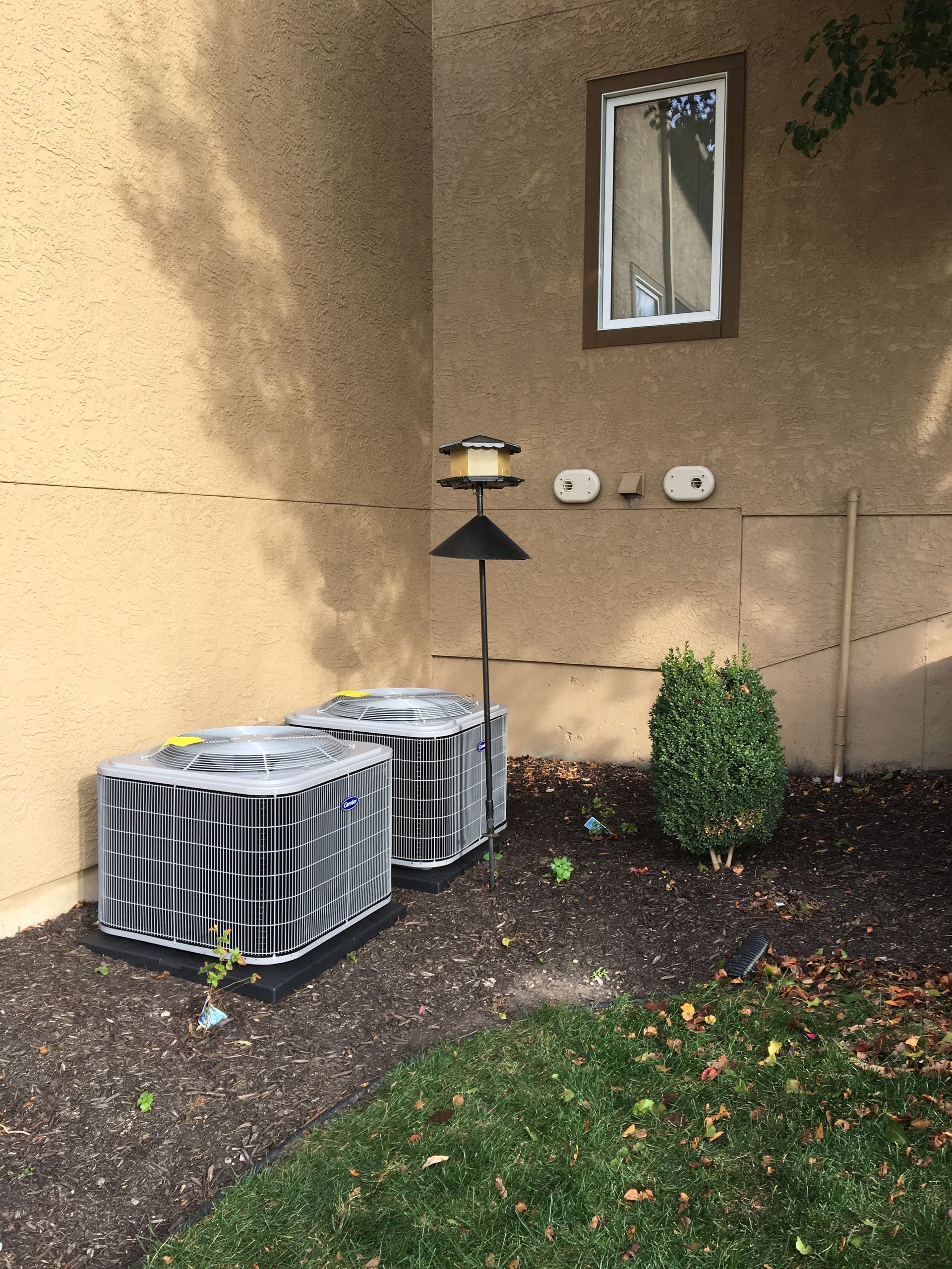 Two air conditioners are sitting in front of a building