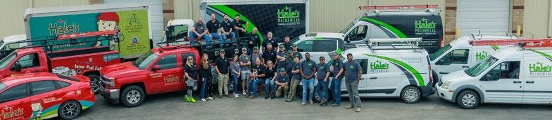 A group of people are posing for a picture in front of a row of trucks.