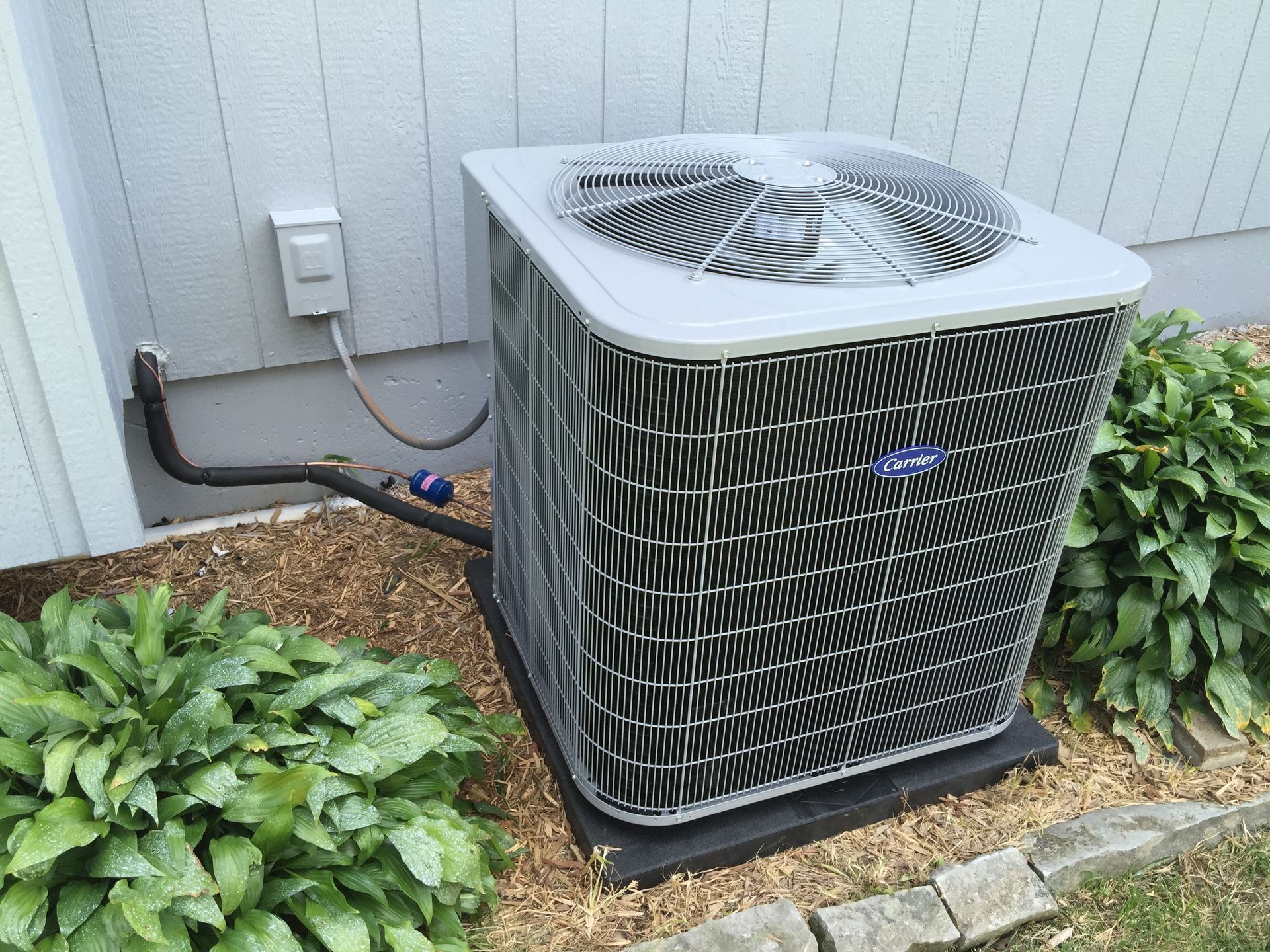 A large air conditioner is sitting outside of a house.