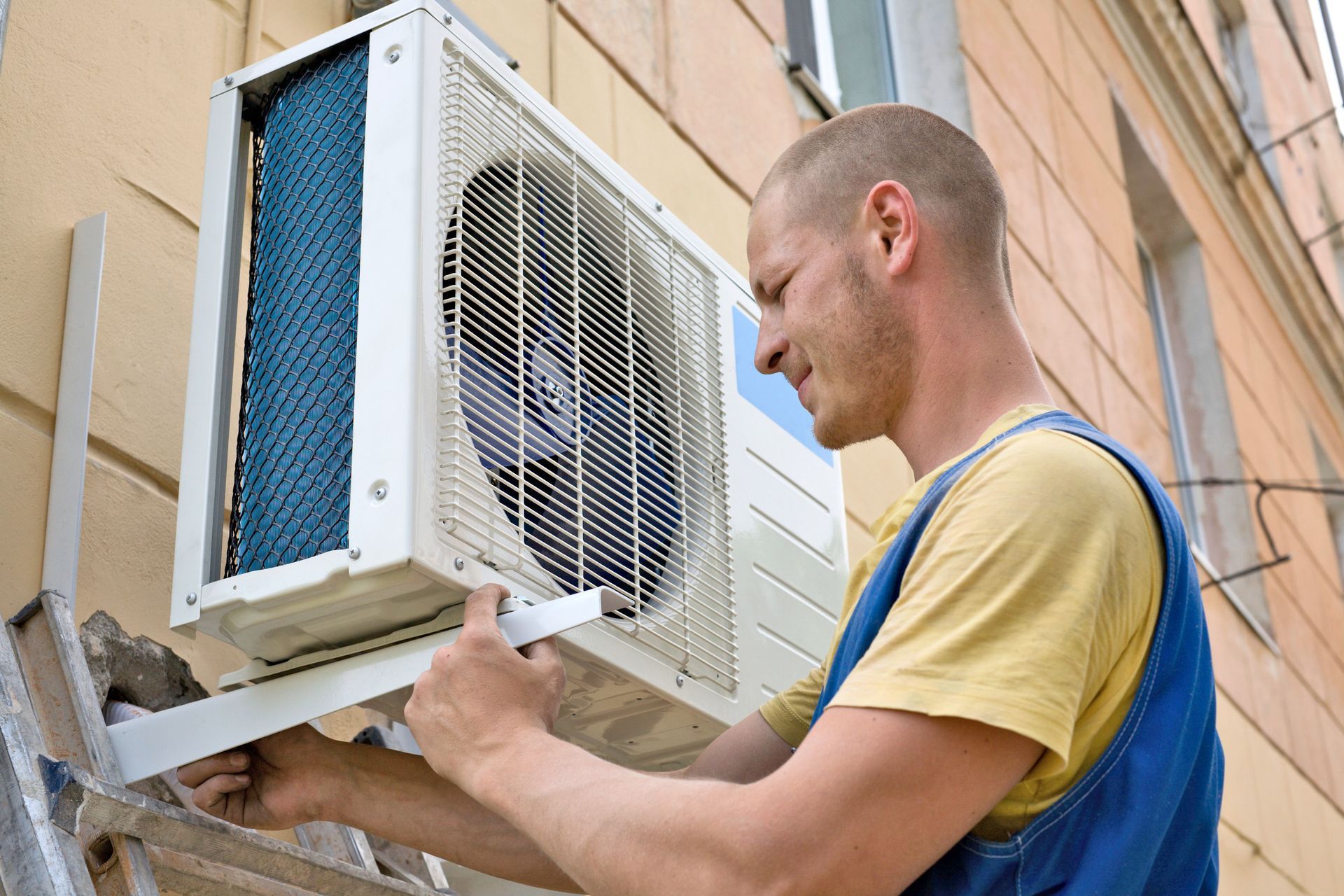 Man installing an air conditioner unit on a building exterior.