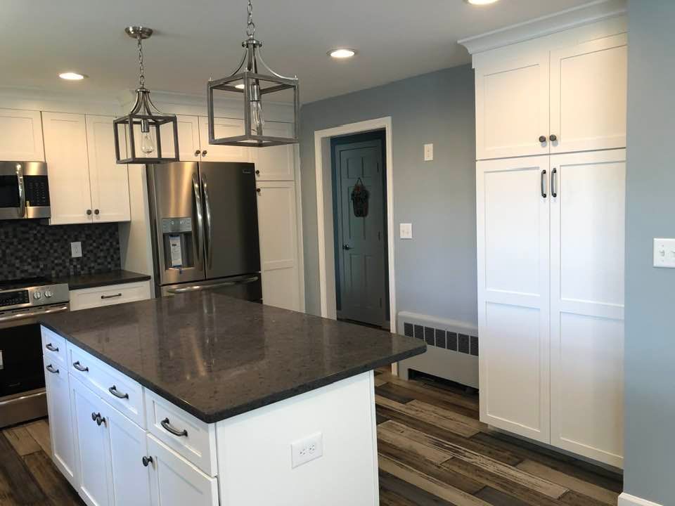 Modern kitchen with white cabinets, dark countertops, stainless steel appliances, and an island.