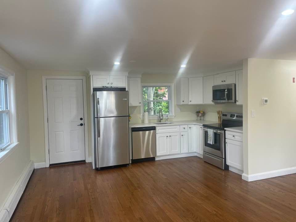 Bright kitchen with white cabinets, stainless steel appliances, and hardwood floors.