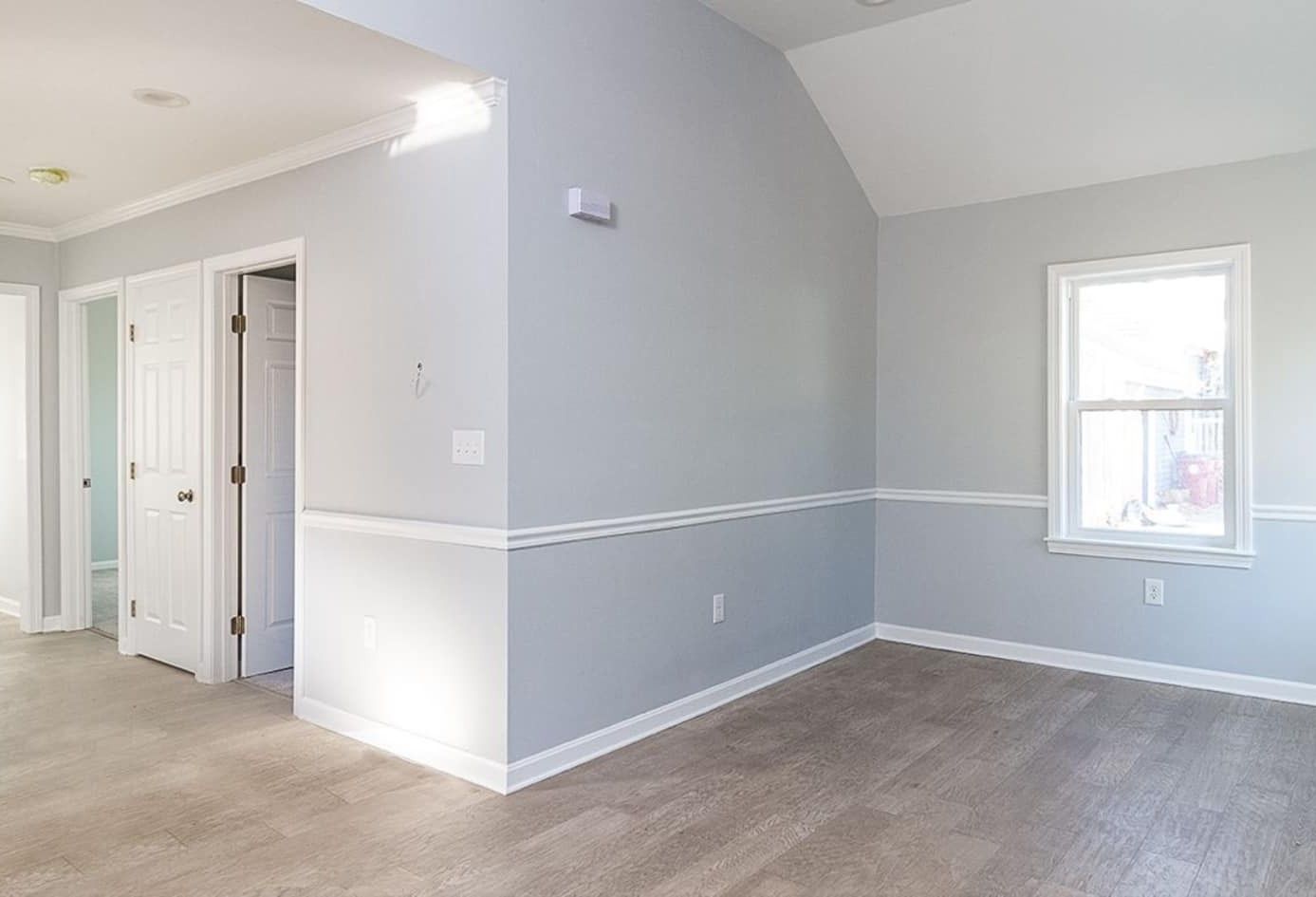 Empty room with gray walls, white trim, and carpet. Includes window and doors.