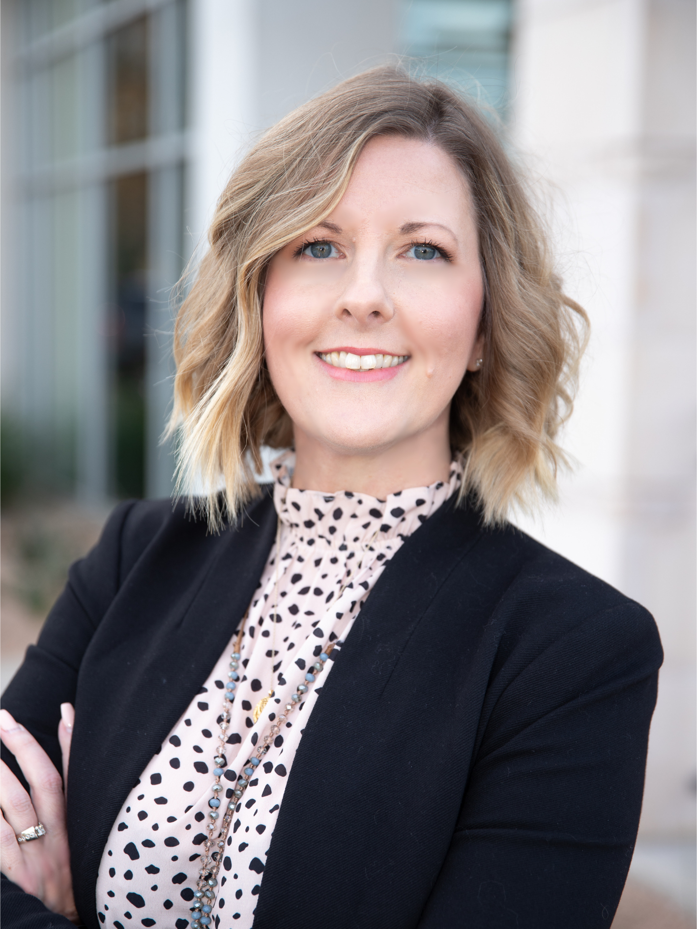 A woman in a black jacket and polka dot shirt is smiling for the camera.