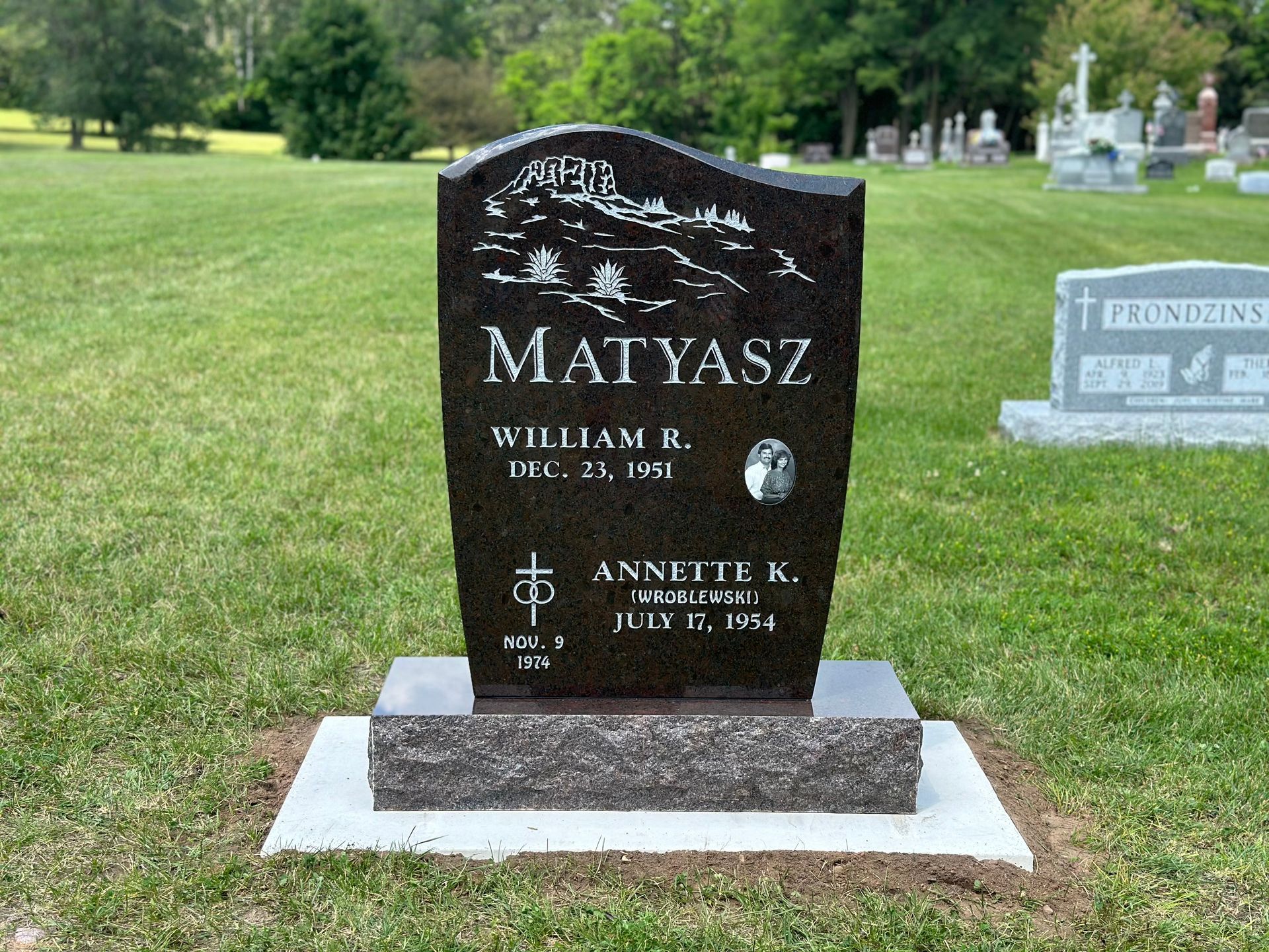 A dark, polished granite upright grave marker for the Matyasz family in a cemetery, featuring engraved text and dates.