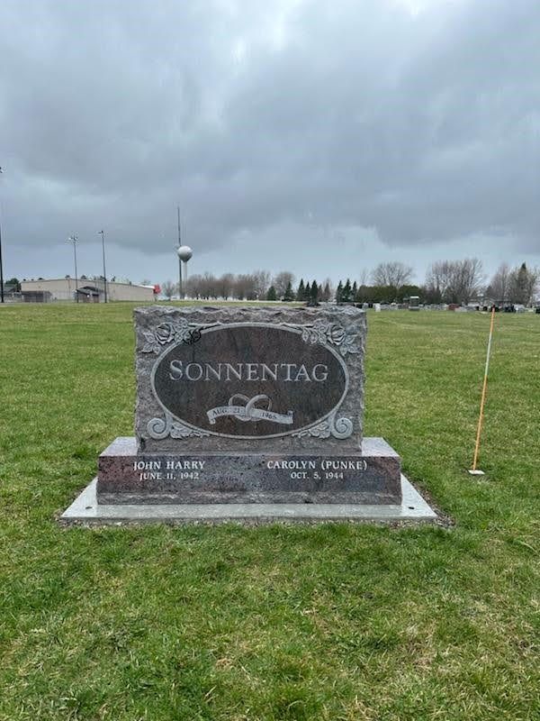 A gray, ornate granite headstone engraved with 