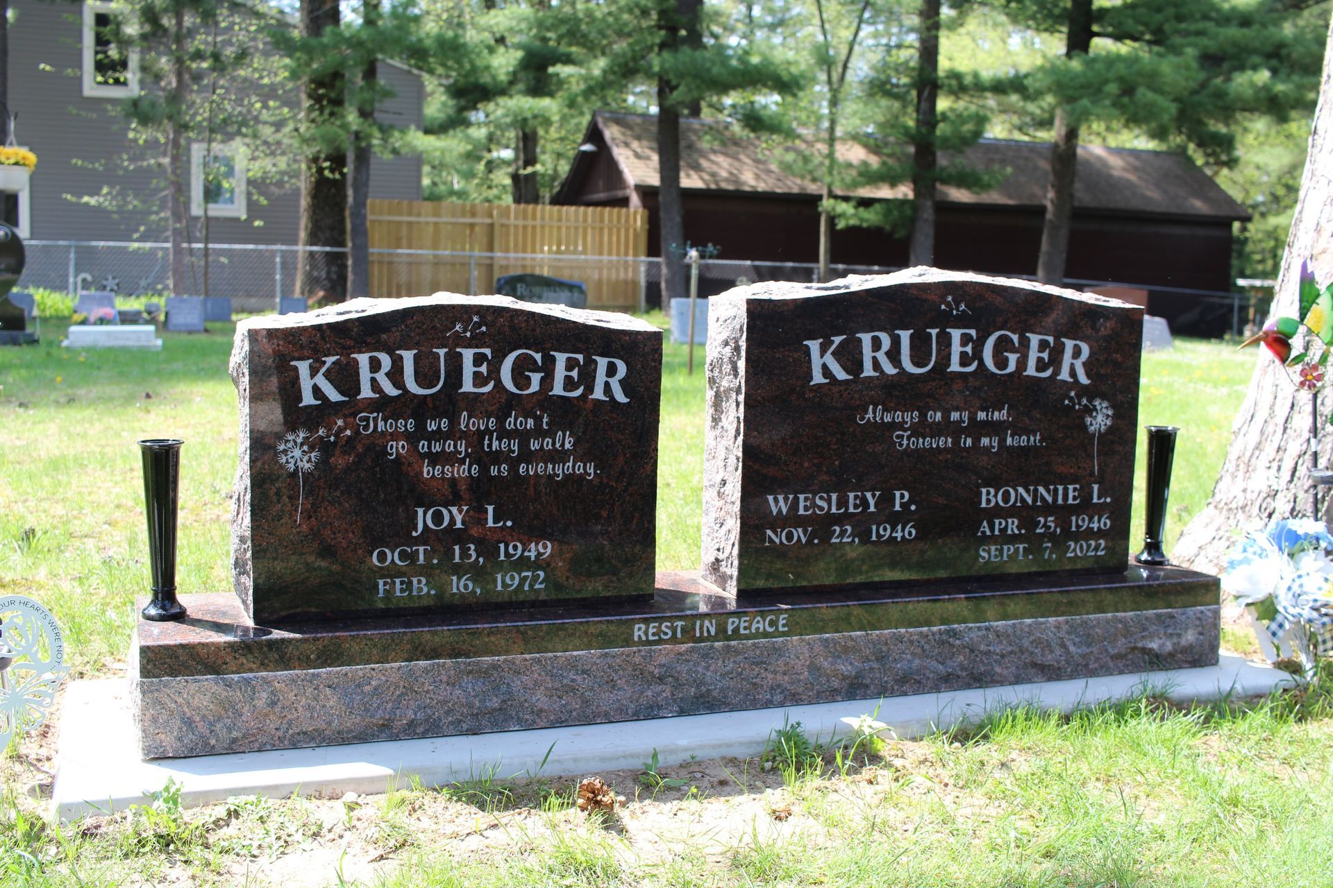 A double granite tombstone for the Krueger family in a cemetery, with names and dates inscribed on the polished surfaces.
