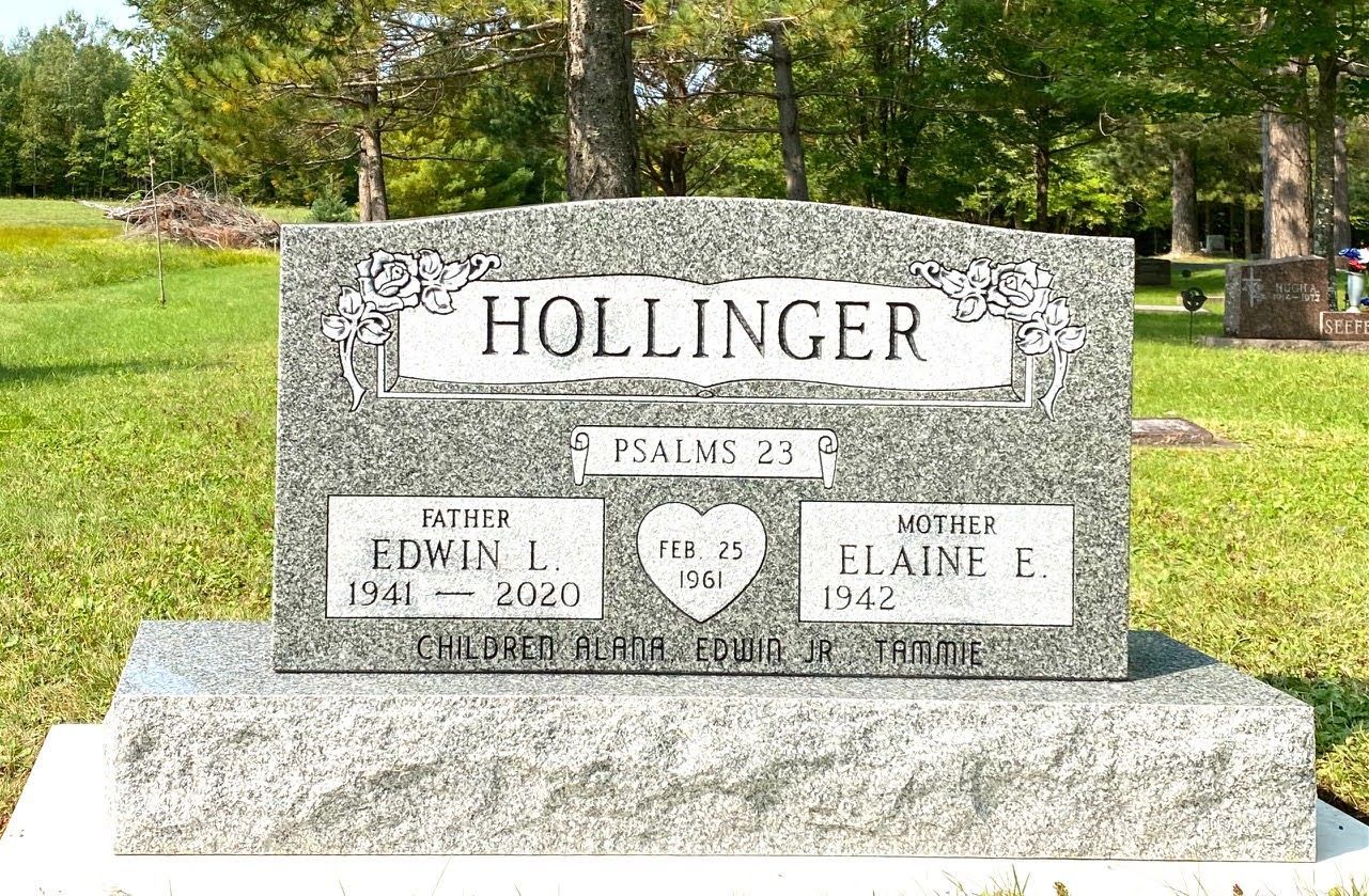 A grey granite headstone for the Hollinger family in a grassy cemetery, featuring names, dates, and a heart inscription.
