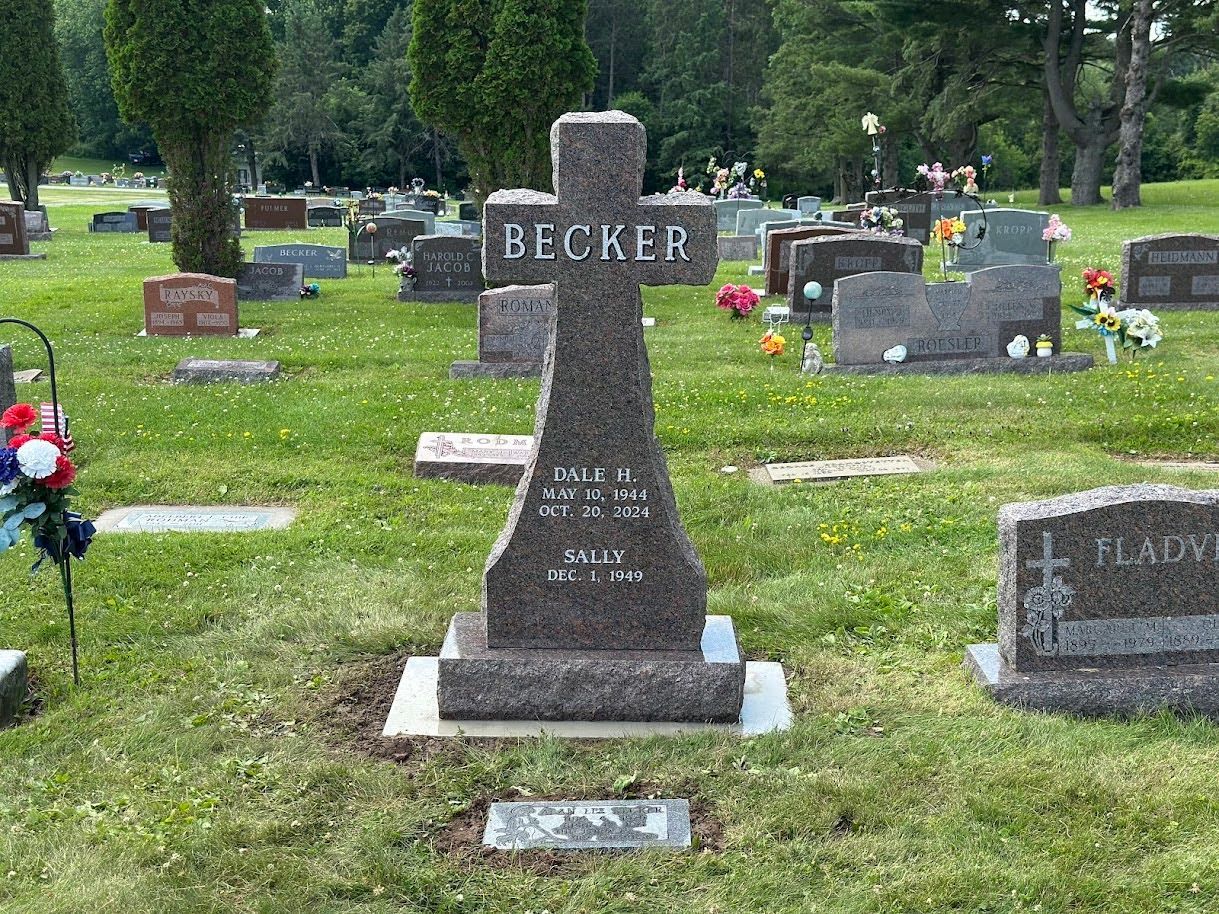 A brown granite cross headstone engraved with 
