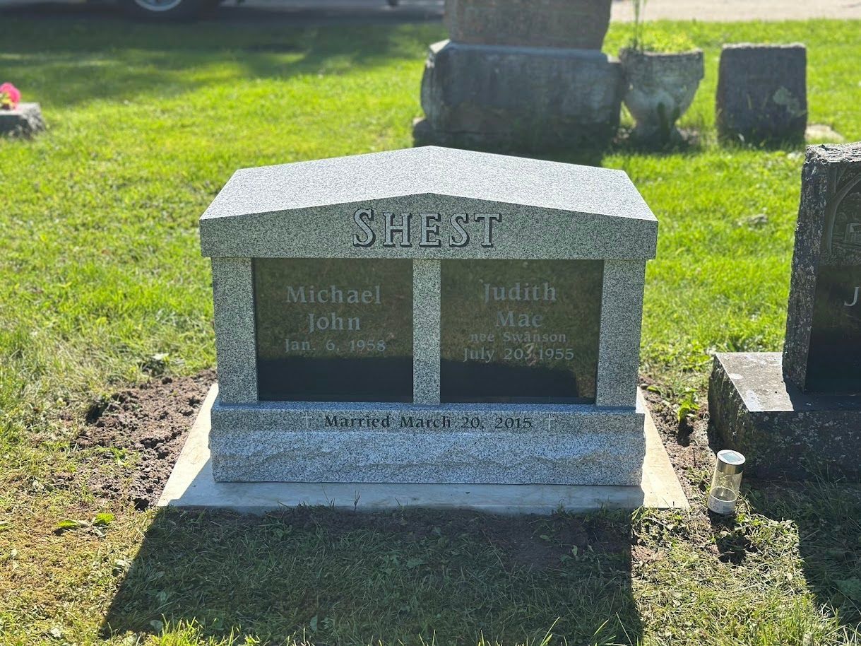 A granite double headstone for the Shest family in a cemetery, featuring the names Michael John and Judith Mae.