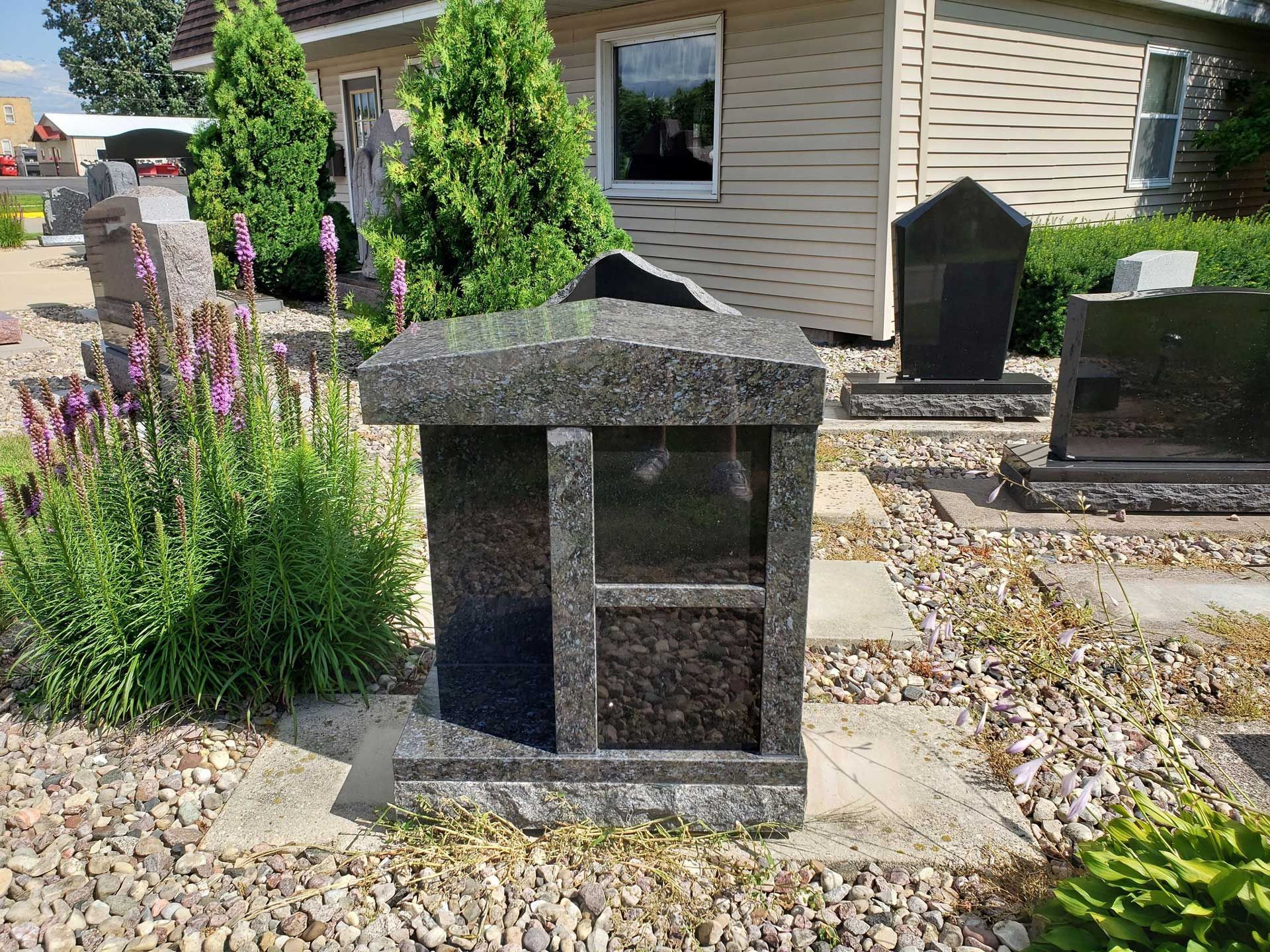 A small gravestone is sitting in a graveyard in front of a house.