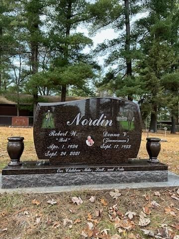 A gravestone in a cemetery with trees in the background.