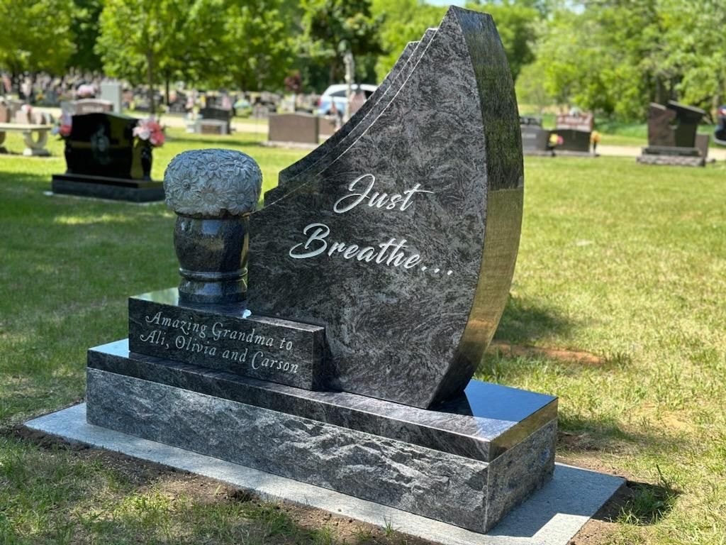 A gravestone in a cemetery with the words `` just breathe '' written on it.