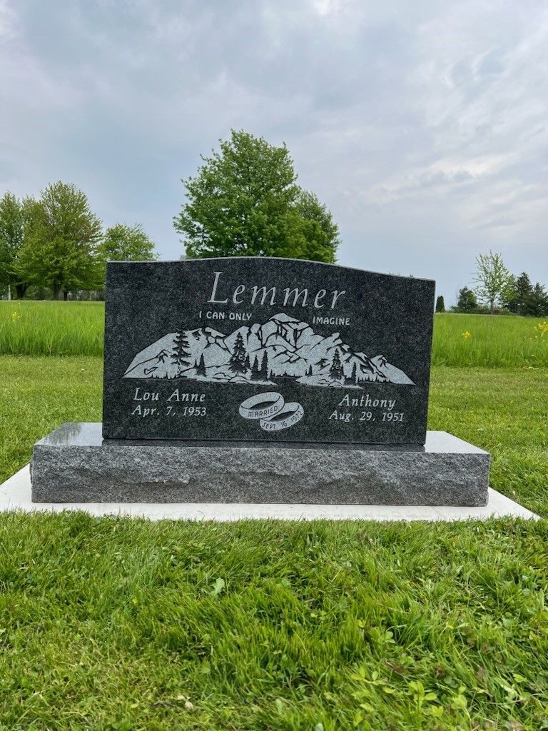 A black gravestone is sitting in the middle of a grassy field.
