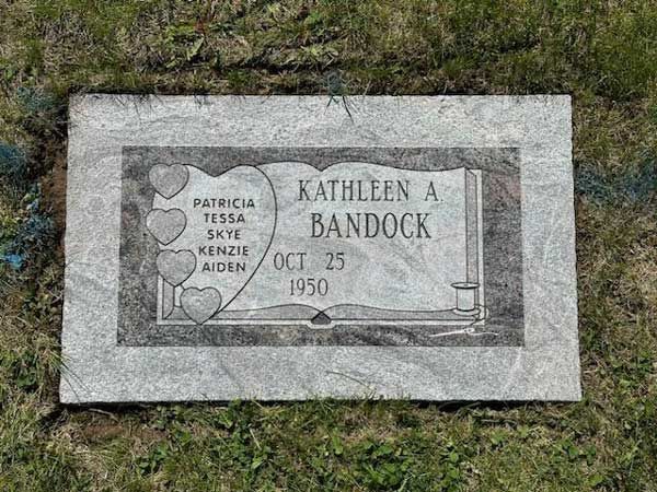 A gravestone for kathleen a bandock is in the grass.