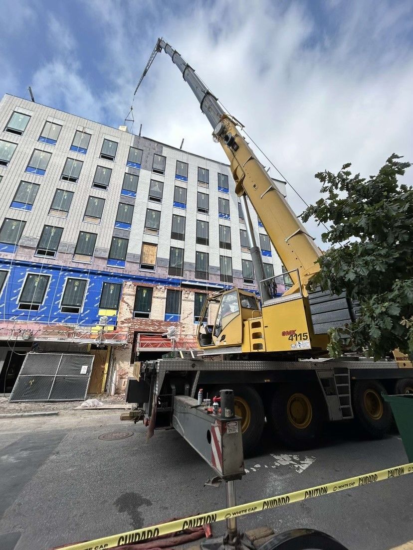 a large yellow crane is parked in front of a building under construction .