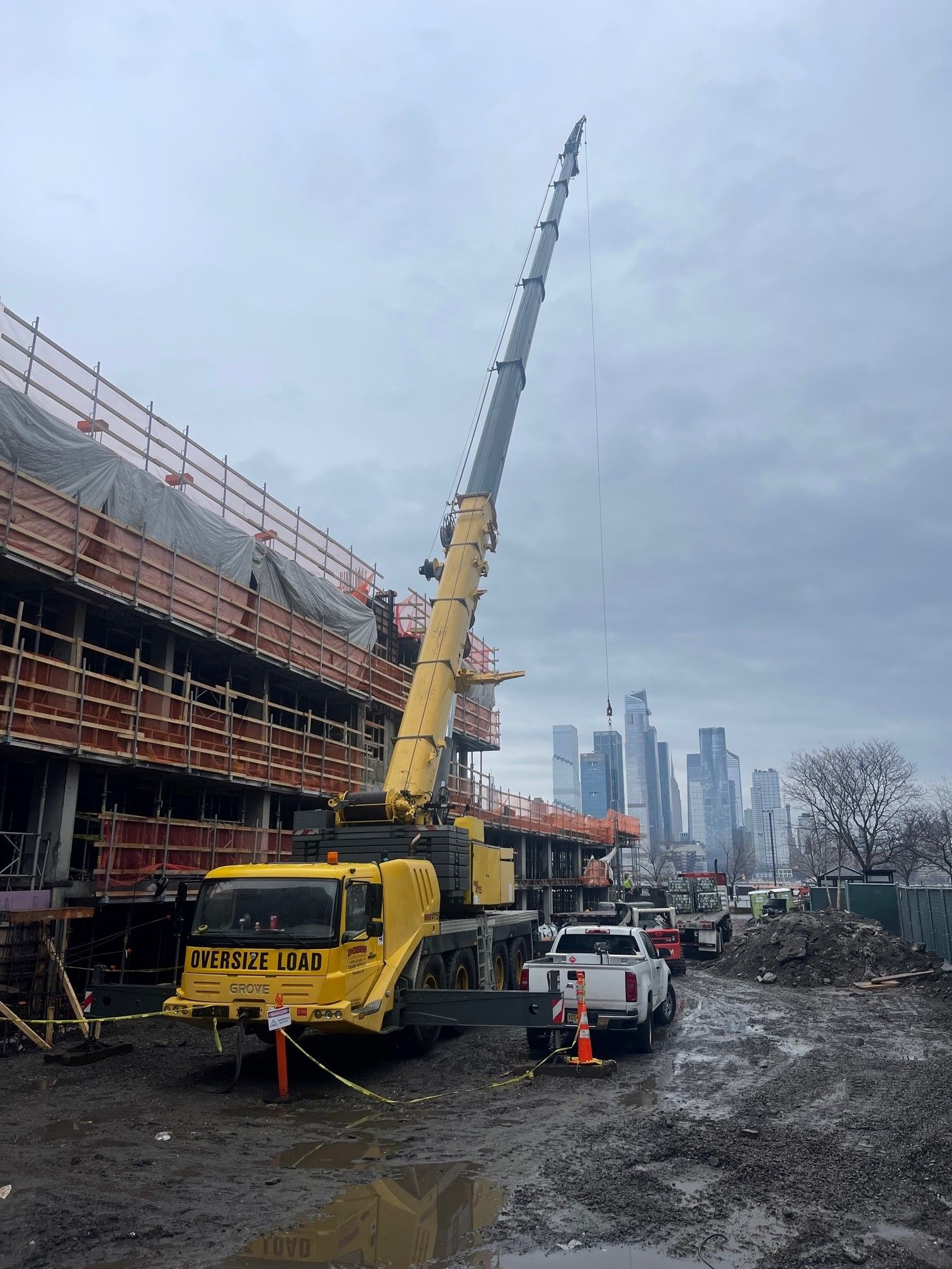 a large yellow crane is parked in front of a building under construction .