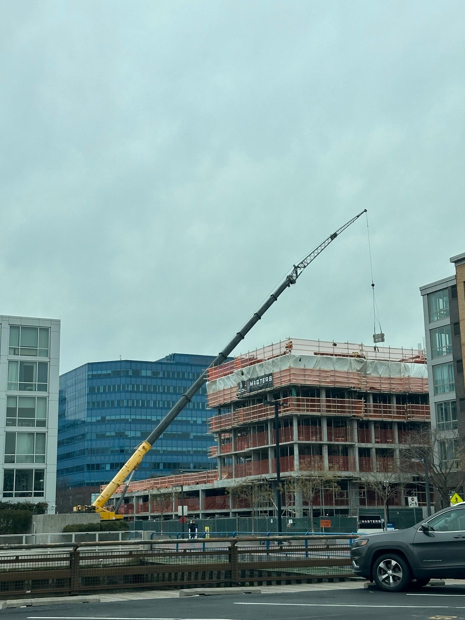 a truck is driving down a street in front of a building under construction .