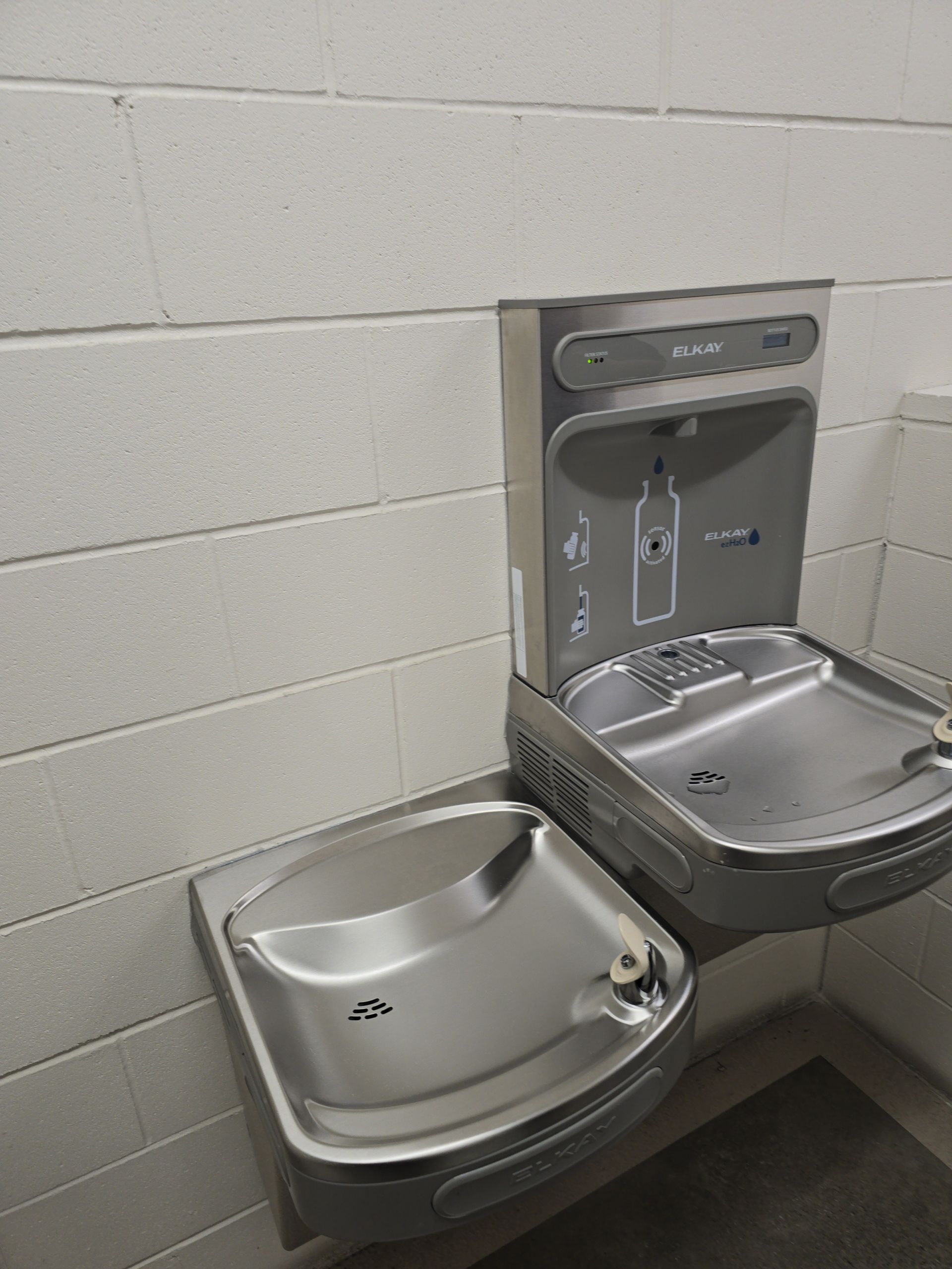 Accessible drinking fountain beside a wheelchair-accessible bottle filler in a tiled wall niche