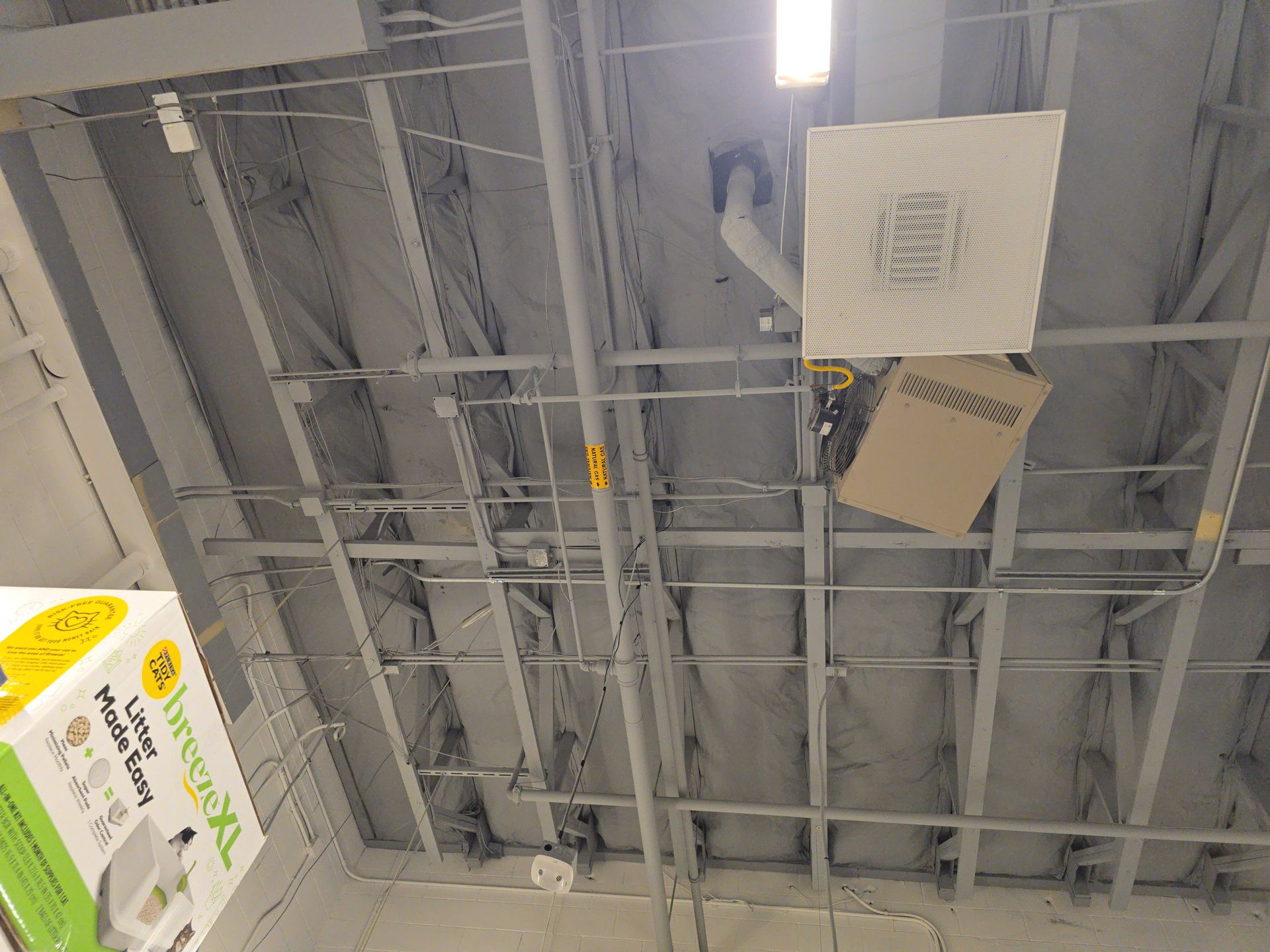 Ceiling with exposed beams, ducts, and hanging vents in an industrial interior.
