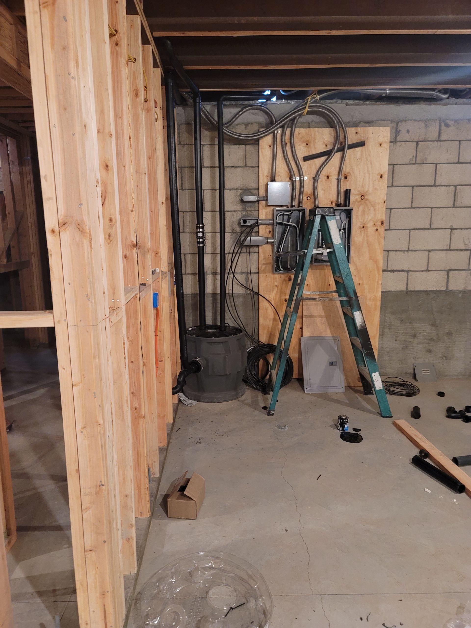 Basement work area with ladder, tools, exposed framing, and cinder block wall.