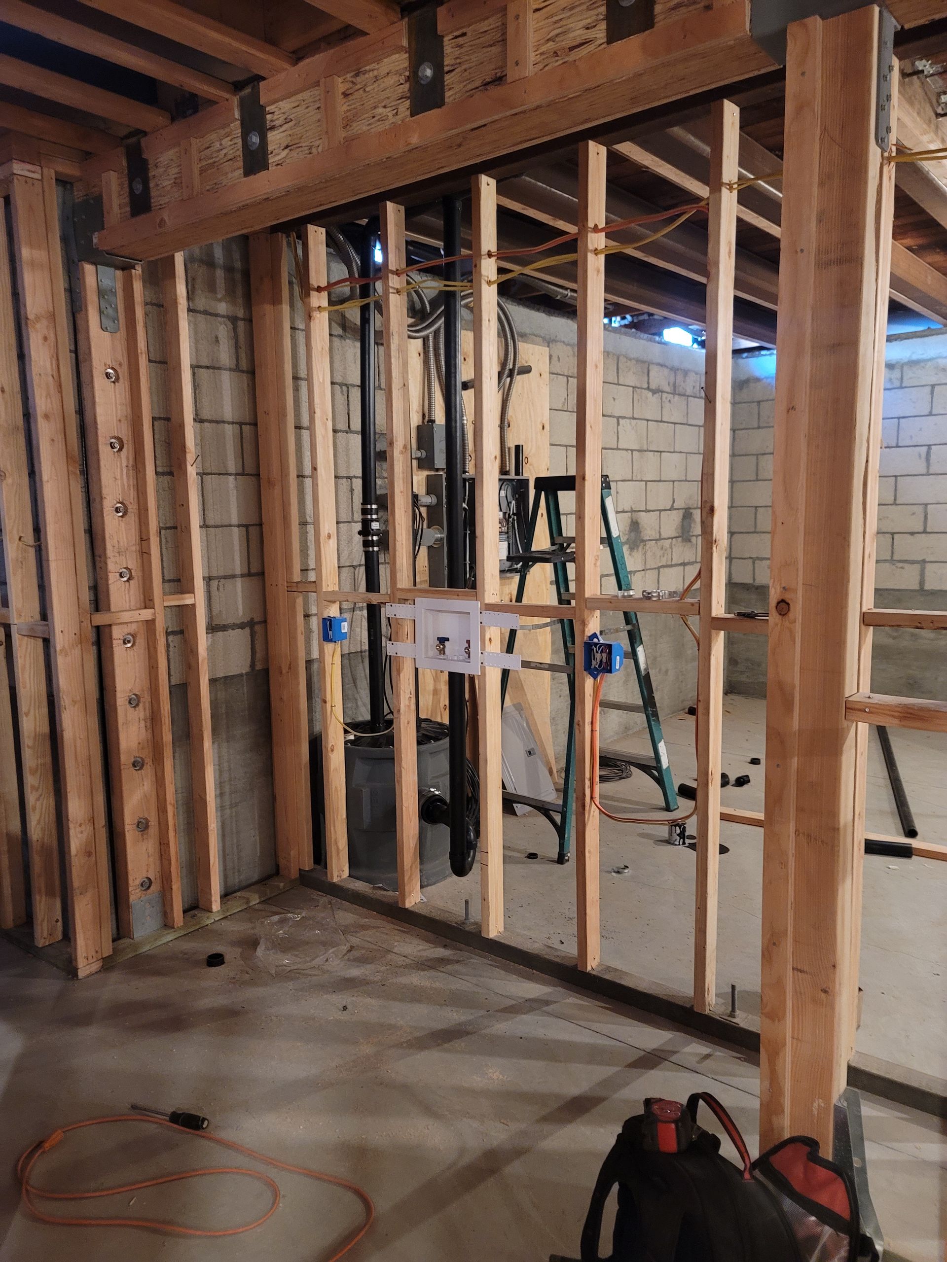 Basement under construction with exposed wood framing, insulation, scaffolding, and concrete floor