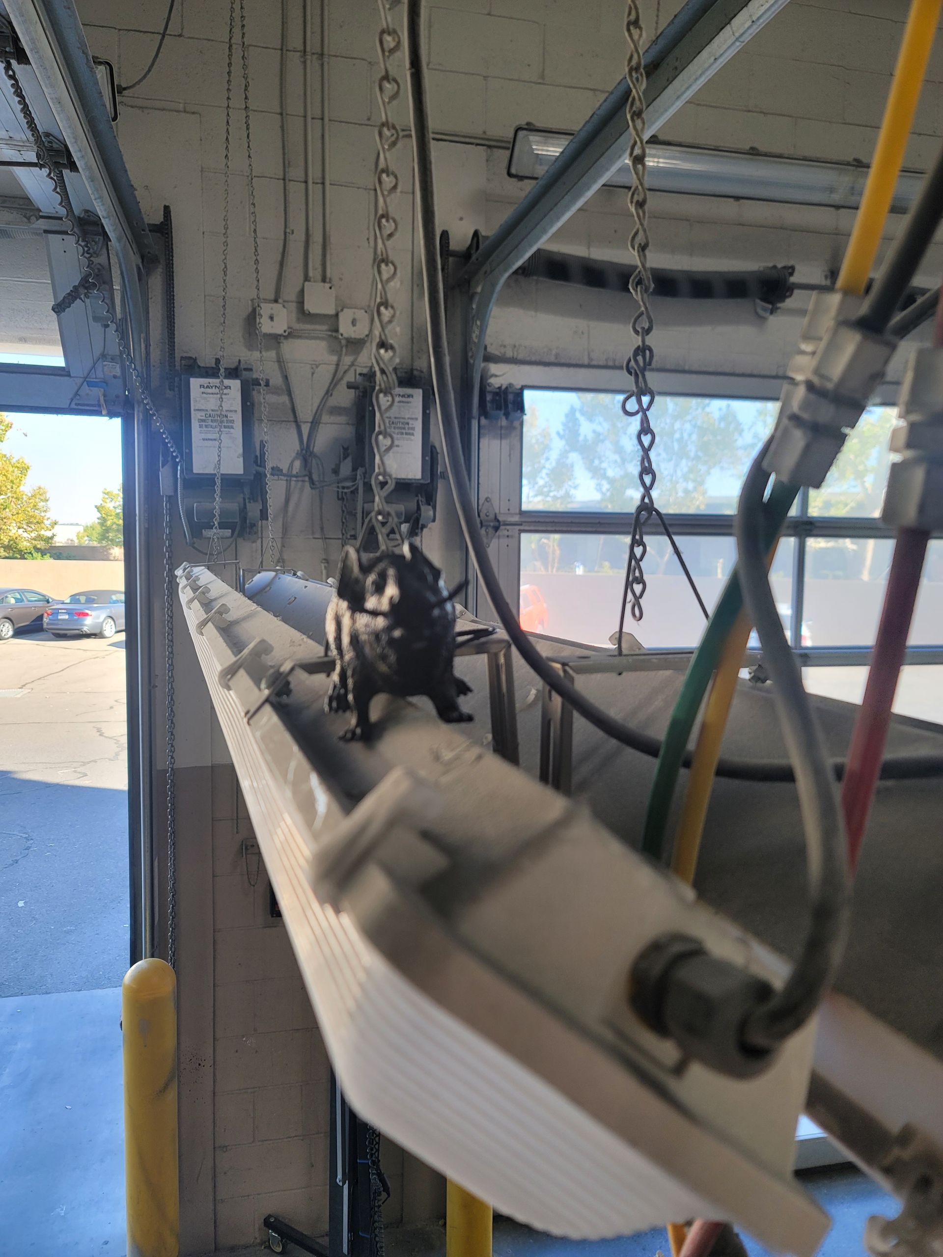 Hanging surfboard in a surf shop garage with chains and repair tools in the background