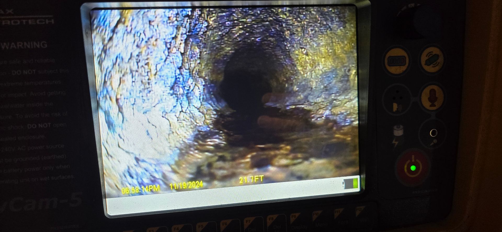 A monitor displays a dark scene with bright yellow-blue textures, beside control dials and a green indicator light