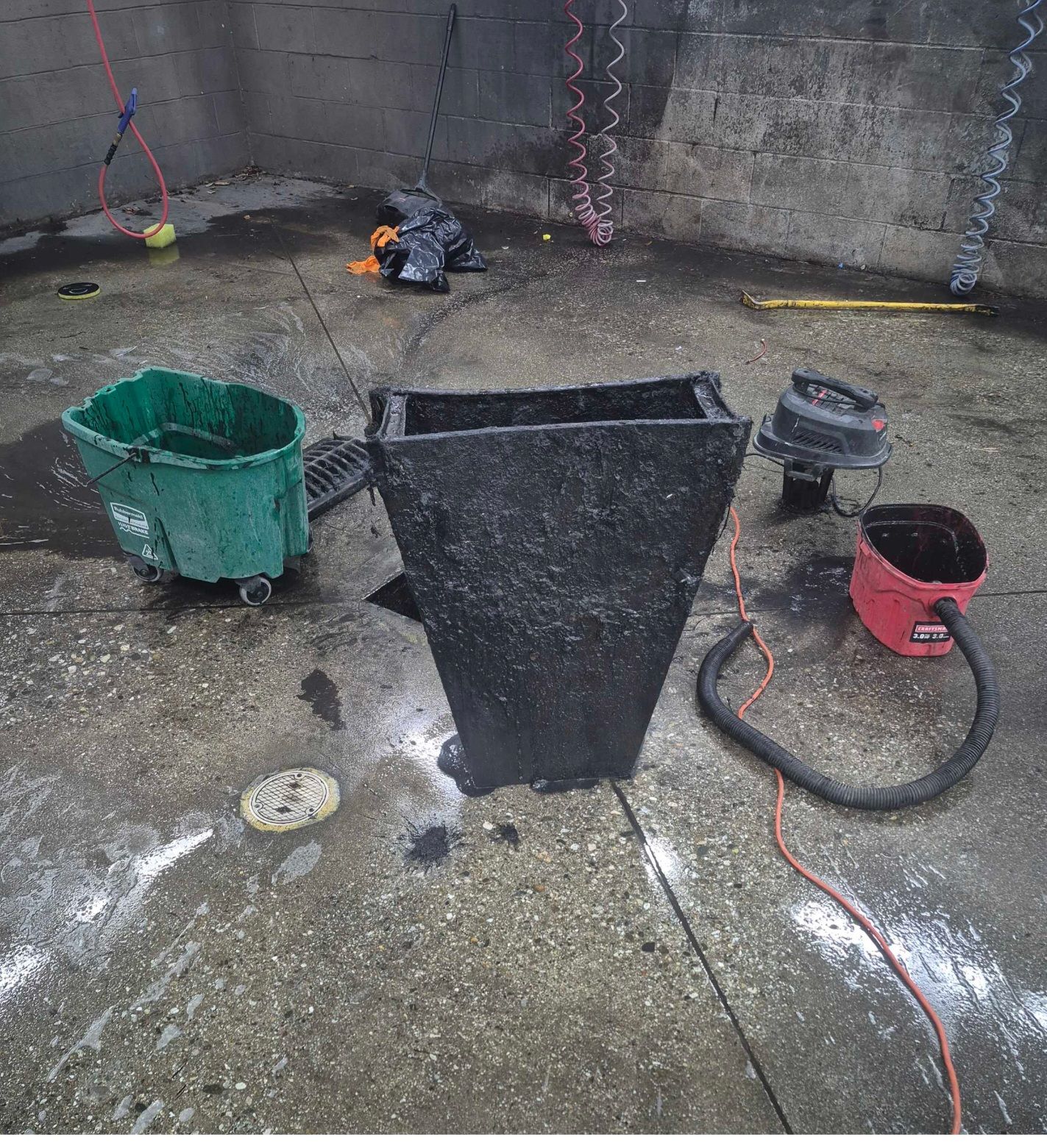 Concrete floor with buckets, hose, and a small work light in an industrial-looking area