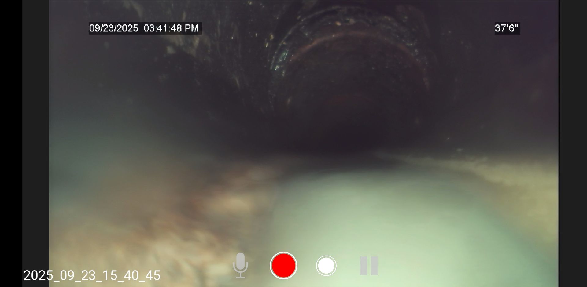 Dark underwater view with a bright beam and camera UI overlays, suggesting a dive or submerged scene